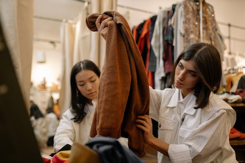 Two people inspecting clothing items at a thrift store